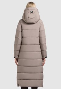 Polstret lang frakke i lys beige med en aftagelig hætte, der har et strømlinet design, vandret quiltning og et cirkulært logo på ryggen.