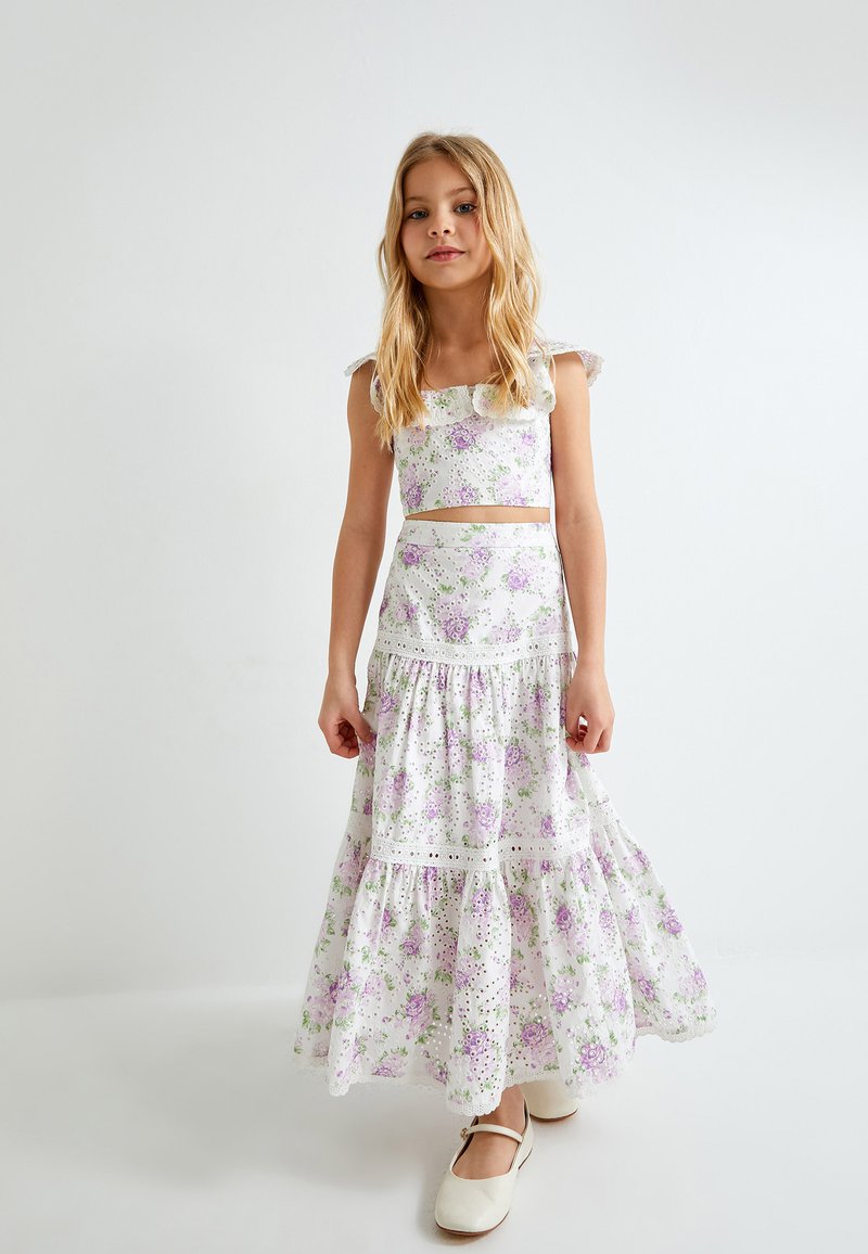 Witte bloemen twee-delige outfit met een crop top met ruches op de schouderbanden en een tiered, enkellange rok, versierd met paarse en groene bloemen.