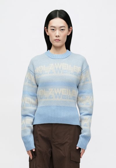 Pull tricoté bleu clair avec poignets et ourlet côtelés, présentant un motif ton sur ton "HOLZWEILER" en crème sur le corps et les manches.