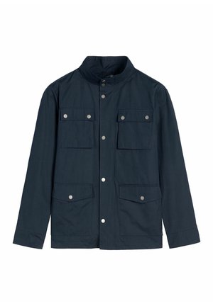 Granatowa kurtka z kołnierzem typu stójka, zapinana z przodu na zatrzaski, z czterema klapowymi kieszeniami z srebrnymi zatrzaskami, przedstawiona na białym tle.
