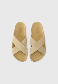 Sandale bej cu barete încrucișate, fabricate din suede moale. Design cu vârf rotunjit și deschis, având o talpă netedă, cu o textură subtilă și branding minim.