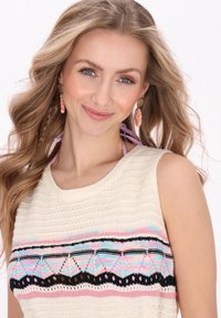 Top tricotat de culoare crem, având dungi orizontale colorate cu modele. Stilizat cu un decolteu rotund și design fără mâneci.