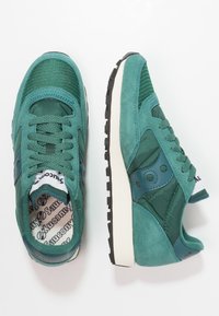 Baskets teal en mesh et en daim, avec un dessus texturé, un système de laçage, une semelle intermédiaire blanche et un design de semelle intérieure à motifs.