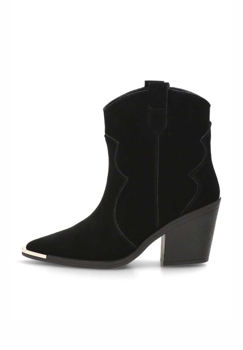 Bota de tobillo de ante negra con puntera puntiaguda, detalles curvados y un tacón grueso. Presenta un pequeño tirador en la parte posterior y un acento metálico en la puntera.