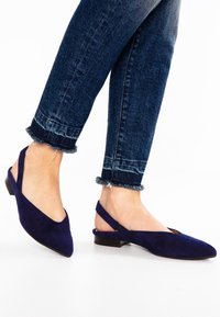 Marineblå ruskind slingback-flats med spids tå og lav blokhæl. Designet har en udskæring foran og en elastisk rem.