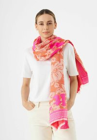 Großer Schal mit Blumenmuster in Farbverläufen von Orange und Pink, mit fransigen Rändern und kräftigen pinken Akzenten. Leichter, strukturierter Stoff.