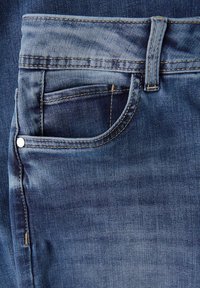 Jean en denim bleu avec une coupe droite, une poche avant avec un rivet en argent, et des détails de couture visibles le long de la taille et de la couture.