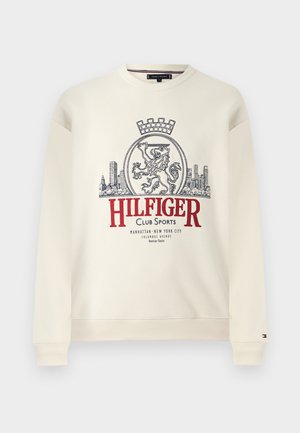 Crèmekleurige sweatvest met geribbelde boorden en zoom, voorzien van een groot leeuwenkader en de tekst "HILFIGER Club Sports" in rood en donkerblauw.