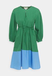 Robe en coton vert avec de longues manches bouffantes, un col rond et une taille à nouer. Présente un ourlet bleu clair et une patte de boutonnage à l'avant avec une fermeture éclair partielle.