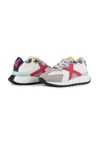 Scarpe da ginnastica con una tomaia in rete e pelle scamosciata bianca, grigia e rossa, dotate di un tacco blu, suola nera e accenti colorati sul colletto.