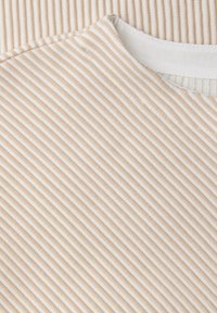 Beżowo-białe paski na tkaninie o żebrowanej fakturze, z gładkim dekoltem i kontrastową białą lamówką wzdłuż krawędzi kołnierza.