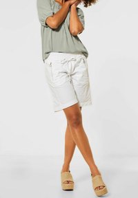 Witte katoenen shorts met zijzakken met rits, elastische tailleband en trekkoord. Gecombineerd met een losvallend saliegroen topje en beige espadrilles.