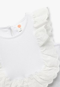 Vestido blanco con un cuerpo texturizado y una manga acampanada con volantes y un intrincado bordado de ojetes. Cierre de cremallera en la parte posterior para una fácil puesta.