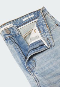 Light blue denim jeans with zipper partially open, button fastened, and visible brand and size labels inside the waistband.
