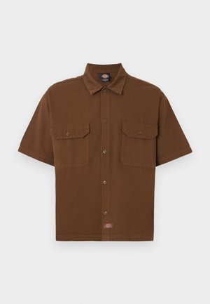 Καφέ κοντομάνικο πουκάμισο με κουμπιά, δύο μπροστινές τσέπες με καπάκι και μικρή ετικέτα με το λογότυπο της μάρκας κοντά στο κάτω κέντρο.