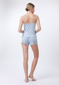 Camisola bleu deschis cu bretele subțiri și pantaloni scurți asortați, care au dantelă pe margine. Țesătură moale cu un design ajustat.