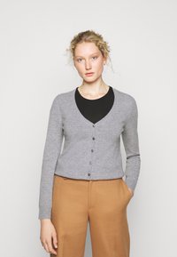 Grå cardigan med V-hals, lange ermer og frontknapper. Laget av mykt materiale, med en tettsittende design og minimal tekstur.