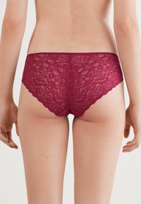 Bordeaux-lace hipster slips met een bloemenpatroon, golvende randen en delicate texturen. Achteraanzicht dat de pasvorm en het ontwerp toont.