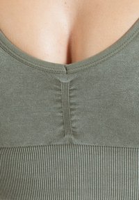 Olijfgroene geribbelde tanktop met een ronde halslijn en subtiele verticale naden op de rug, die textuur en een nauwsluitende pasvorm bieden.