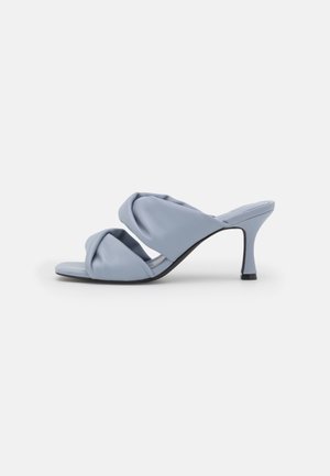 Light blue open-toe mule with padded twisted straps and a slim mid-height heel on a white background.