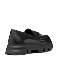 Mocasines de cuero negro con una suela de goma gruesa, que cuentan con un acento texturizado cerca del talón y un sencillo detalle de tira en la parte superior.