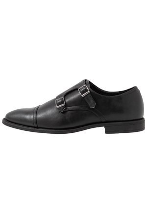 Sort lædersko med dobbelt monk-strap spænder, rundet tå og lav hæl, vist fra ydersiden.