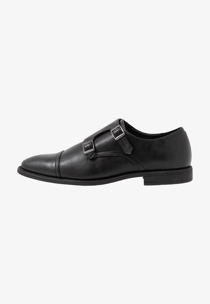 Chaussure habillée en cuir noir avec doubles brides à boucles de moine, bout arrondi et talon bas, vue de côté extérieur.