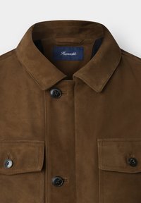Braune Wildlederjacke mit umgeschlagenem Kragen, vorderem Knopfverschluss und zwei Brusttaschen. Verfügt über schwarze Knöpfe und ein blaues Innenetikett.