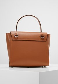 Sac à main en cuir marron avec une forme structurée, une poignée supérieure et un rabat de fermeture avec quincaillerie en argent. Surface texturée avec un grain subtil.