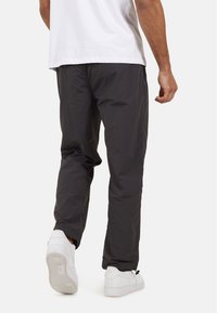 Ciemnoszare, lekkie spodnie o gładkiej fakturze, zwężającym się fasonie i elastycznym pasie, zestawione z białymi trampkami.