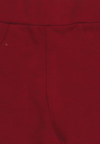 Rote Baumwollhose mit einer glatten Textur, genähten Nähten und zwei Vorderentaschen. Der Stoff wirkt weich und langlebig.