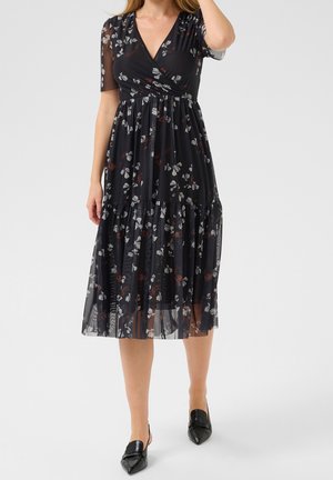 Czarna sukienka w kwiaty z kopertowym dekoltem, krótkimi rękawami i falbanistym dołem. Wykonana z lekkiego materiału w białe i czerwone wzory kwiatowe.