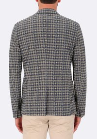 Blazer a quadri blu navy e beige con vestibilità sartoriale, dotato di revers a punta e doppia apertura sul retro. Tessuto testurizzato con polsini con bottone.