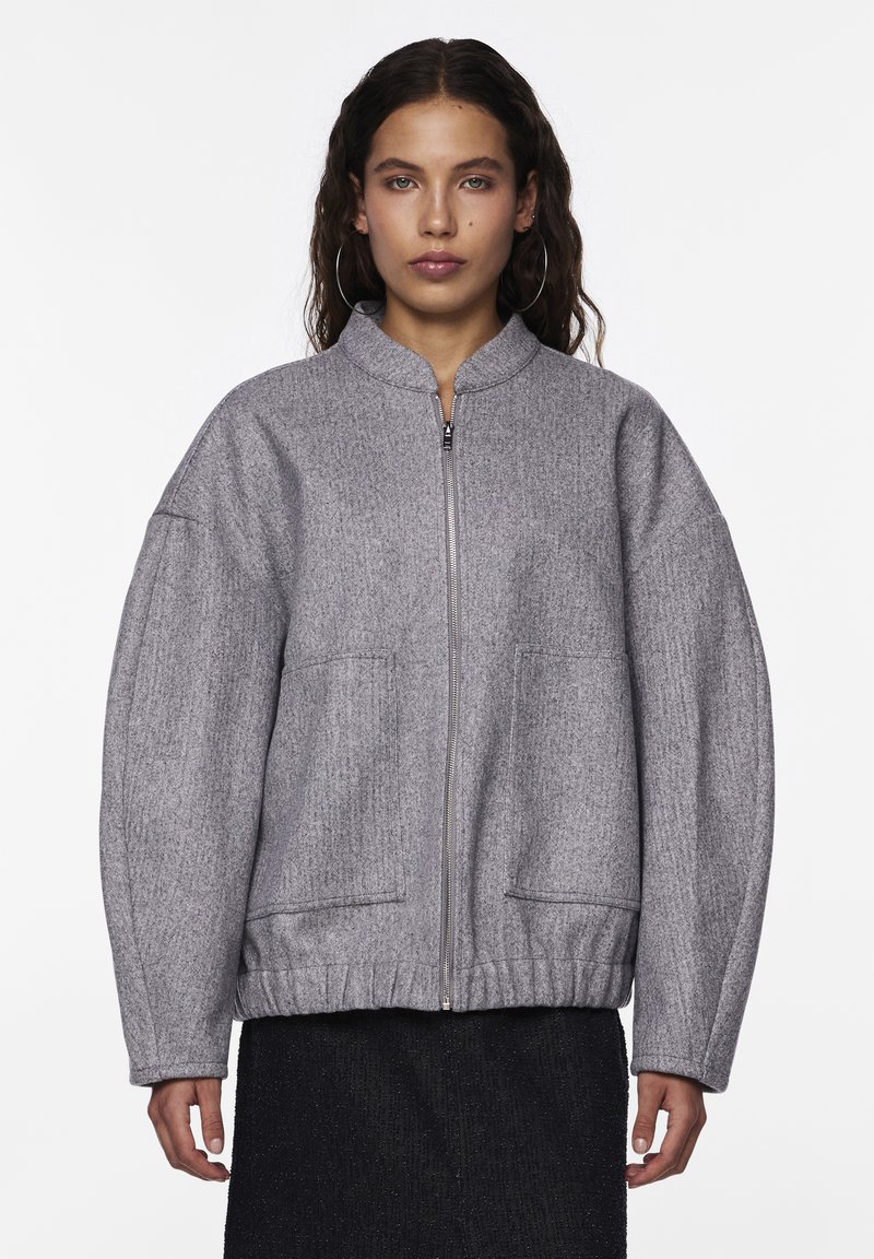 Grå zip-up jacka med texturerad yta, funnel neck och oversized silhuett. Har två framfickor och elastisk nederkant.