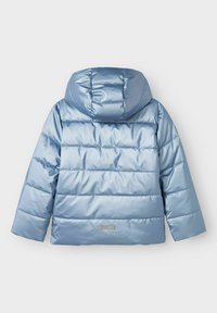 Svijetloplava podstavljena jakna s kapuljačom, horizontalnim šavovima i malom pravokutnom oznakom "TECH" blizu donjeg središnjeg dijela.