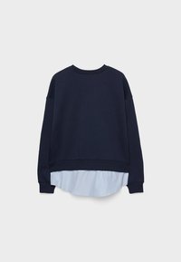 Felpa a maniche lunghe blu navy sovrapposta a una camicia a righe verticali blu chiaro e bianca che spunta sotto l'orlo.