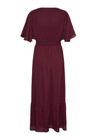 Robe bordeaux longueur au sol avec manches courtes volantées, taille froncée et ourlet à volants vue de dos sur fond blanc.