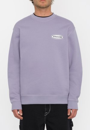 Sweatshirt lilas en tissu doux, avec un col rond, des poignets et un ourlet côtelés, orné d'un logo "Volcom" noir et blanc imprimé sur le devant.