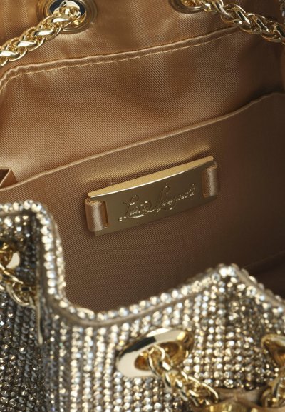 Indersiden af en sølvfarvet paljet-pung med en glat, gylden foring og en guldfarvet mærkeplade. Kædestroppen i metal tilføjer detaljer.