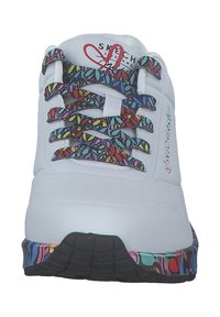 Zapatilla deportiva blanca con cordones de colorido patrón y suela negra que presenta un vibrante diseño multicolor alrededor de la base.