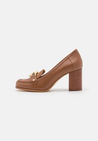 Chaussure à talon haut en cuir marron avec un bout rond et une sangle décorative ornée d'une boucle en ton doré. Talon en bloc texturé.