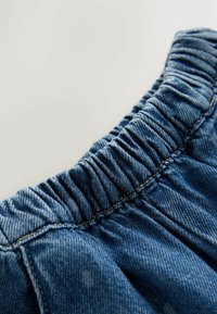 Falda vaquera azul con cintura elástica fruncida y tejido texturizado. Presenta costuras en contraste y un lavado ligeramente desgastado.