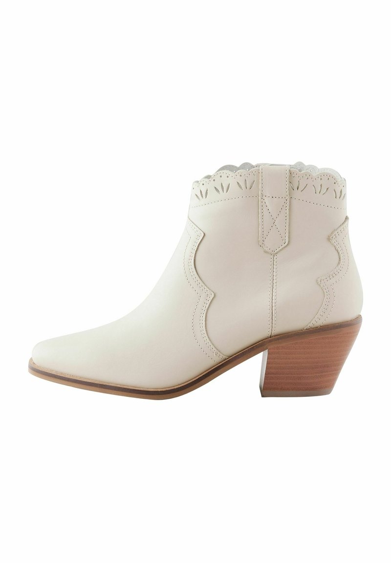 Bottine en cuir blanc avec bord supérieur festonné, couture décorative et talon bloc empilé en bois.
