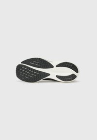 Talpă de pantof sport negru, cu un profil din cauciuc texturat și o intermediară albă, având șanțuri pentru tracțiune și stabilitate.
