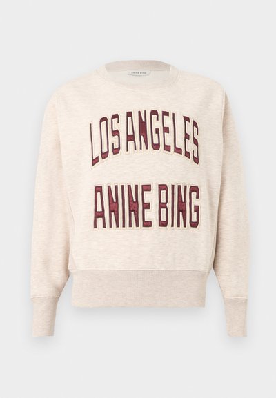 Beige genser med ribbestrikkede mansjetter og nederkant, med store burgunderfargede bokstaver som sier "LOS ANGELES" og "ANINE BING" på fremsiden.