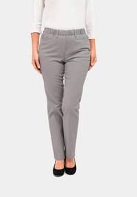 Graue Stretchhose mit einem elastischen Bund und zwei Fronttaschen, schmal geschnitten und mit subtiler vertikaler Textur. Getragen mit schwarzen Schuhen.