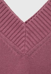 Pulover z V-izrezom v umirjeni taupe barvi, z rebrasto teksturo, diagonalnimi šivi in gladkim, mehkim zaključkom.