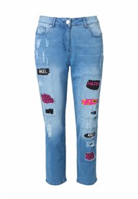 Světle modré džínové kalhoty mají opotřebované detaily, několik záplat s textem a živé vzory v růžové a černé barvě.