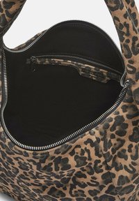 Tasje met luipaardprint en een zwarte binnenkant; heeft een ritssluiting en een klein binnenvak; gladde textuur en ronde vorm.