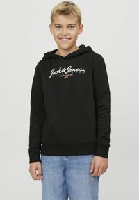 Sudadera negra con detalle del logo en el frontal, hecha de una tela suave, que incluye un bolsillo canguro y puños de canalé, combinada con jeans de color azul claro.